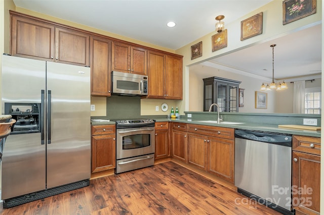 13714 Morehouse St, Huntersville, NC 28078 - kitchen featuring stainless steel appliances, a chandelier, brown cabinets, dark wood-type flooring, and hanging light fixtures