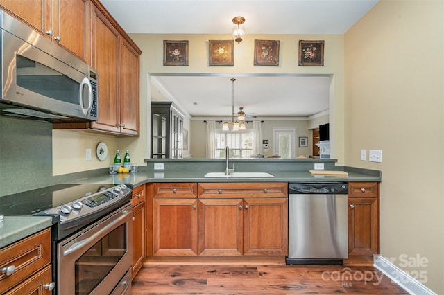 13714 Morehouse St, Huntersville, NC 28078 - kitchen featuring appliances with stainless steel finishes, wood finished floors, a peninsula, brown cabinetry, and dark countertops