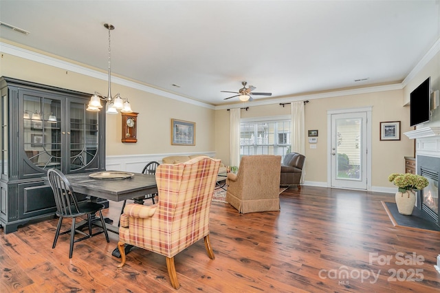 13714 Morehouse St, Huntersville, NC 28078 - dining area with crown molding, wood finished floors, a fireplace with flush hearth, ceiling fan, and a wainscoted wall
