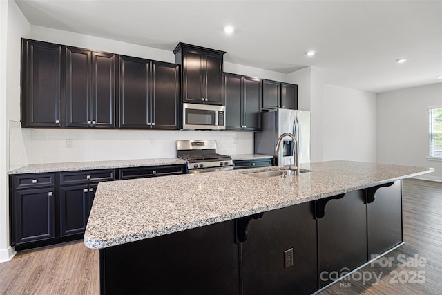2040 Dornoch Rd, Tega Cay, SC 29708 - kitchen featuring appliances with stainless steel finishes, light wood-style flooring, a kitchen bar, an island with sink, and recessed lighting