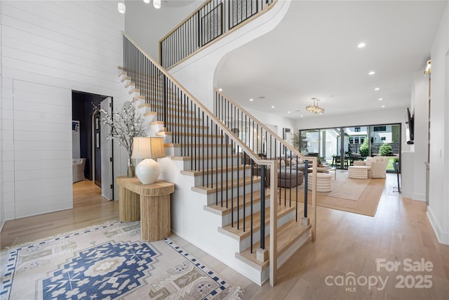 1401 Heather Ln, Charlotte, NC 28209 - staircase featuring wood finished floors, recessed lighting, a towering ceiling, arched walkways, and a chandelier