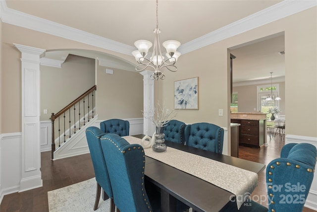 10806 Cove Point Dr, Charlotte, NC 28278 - dining space featuring dark wood-style flooring, a chandelier, crown molding, a wainscoted wall, and decorative columns