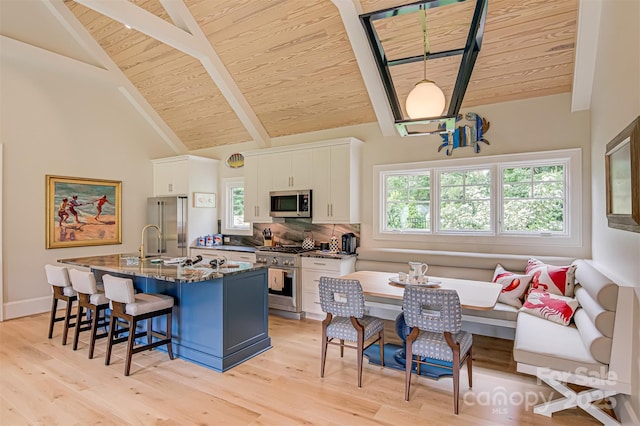 2632 Bartram Pl, Winston Salem, NC 27106 - kitchen featuring high end appliances, a wooden ceiling with exposed beams, a breakfast bar, white cabinetry, and a kitchen island with sink
