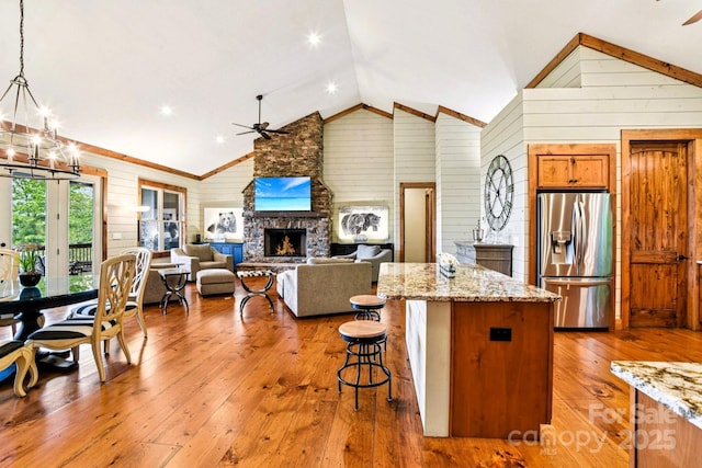 71 Raptor Way, Sapphire, NC 28774 - kitchen featuring stainless steel fridge with ice dispenser, a ceiling fan, wood walls, a fireplace, and hardwood / wood-style floors