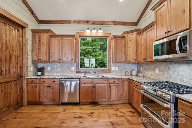 71 Raptor Way, Sapphire, NC 28774 - kitchen featuring appliances with stainless steel finishes, vaulted ceiling, light wood-style flooring, tasteful backsplash, and light stone counters