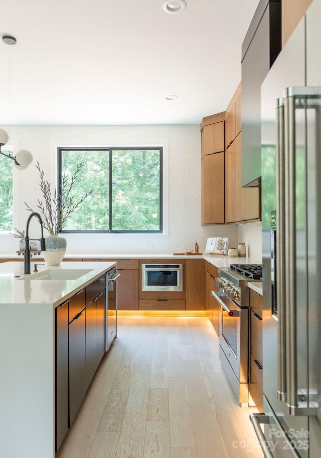 1727 Seifert Cir, Charlotte, NC 28205 - kitchen featuring appliances with stainless steel finishes, modern cabinets, light wood finished floors, light countertops, and hanging light fixtures