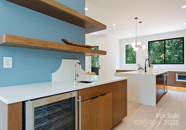 1727 Seifert Cir, Charlotte, NC 28205 - kitchen featuring wine cooler, a kitchen island with sink, light wood-style flooring, open shelves, and light countertops