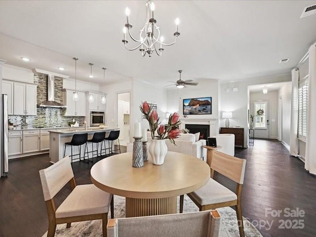 2034 Laney Pond Rd, Matthews, NC 28104 - dining area with dark wood-style flooring, a ceiling fan, a chandelier, a lit fireplace, and recessed lighting