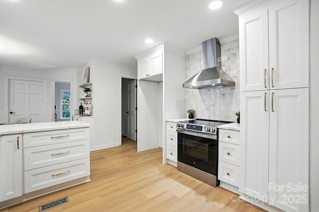 6542 Cross Field Ln, Charlotte, NC 28226 - kitchen with wall chimney range hood, stainless steel range with electric stovetop, tasteful backsplash, white cabinetry, and light wood finished floors