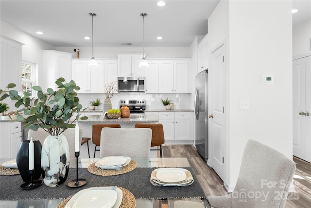 167 Dry Dock Loop, Mooresville, NC 28117 - kitchen with appliances with stainless steel finishes, light wood-type flooring, a breakfast bar, decorative backsplash, and recessed lighting
