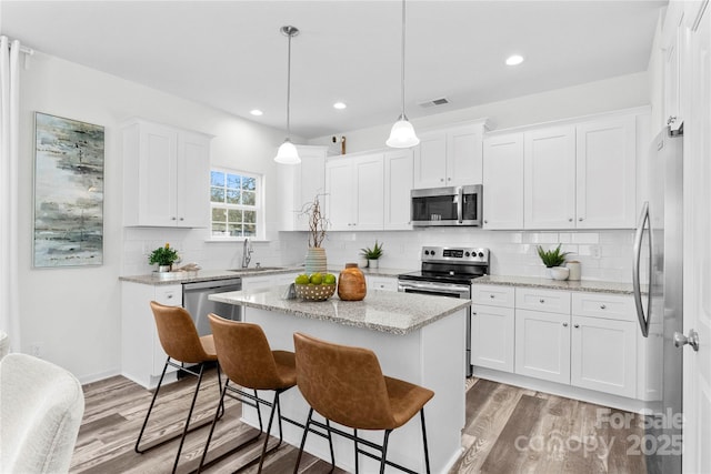 167 Dry Dock Loop, Mooresville, NC 28117 - kitchen with appliances with stainless steel finishes, a kitchen island, light wood finished floors, white cabinetry, and recessed lighting