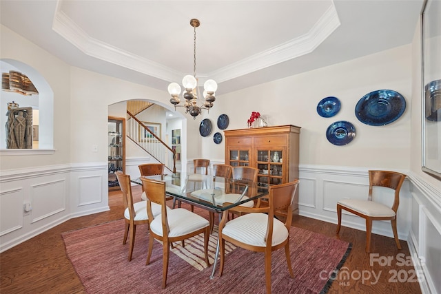 16833 Rudence Ct, Charlotte, NC 28278 - dining area featuring arched walkways, wood finished floors, a chandelier, ornamental molding, and a tray ceiling