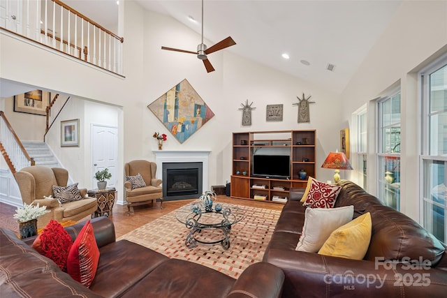 16833 Rudence Ct, Charlotte, NC 28278 - living area featuring high vaulted ceiling, stairway, a ceiling fan, a glass covered fireplace, and wood finished floors