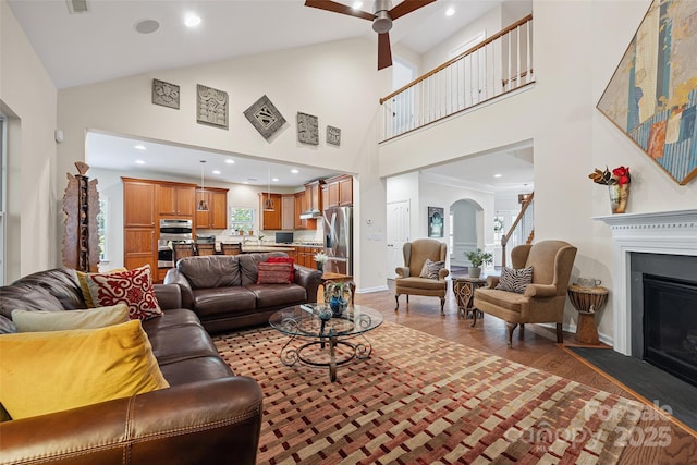 16833 Rudence Ct, Charlotte, NC 28278 - living room featuring a glass covered fireplace, wood finished floors, a ceiling fan, high vaulted ceiling, and arched walkways