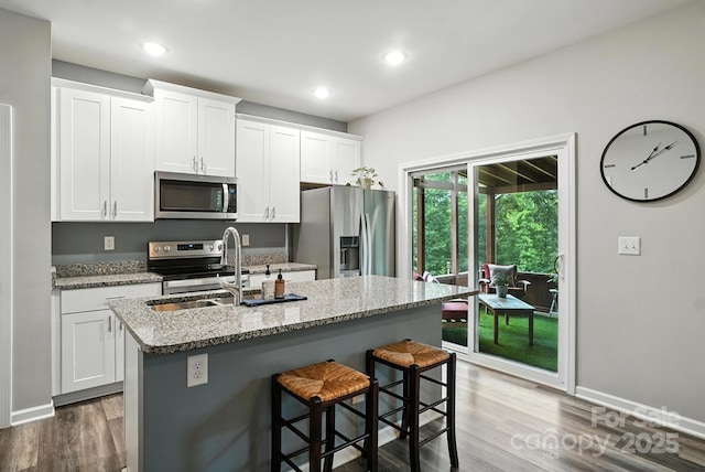 280 Mills Creek Rd, Iron Station, NC 28080 - kitchen with stainless steel appliances, a kitchen island with sink, dark wood-style flooring, a kitchen bar, and white cabinets