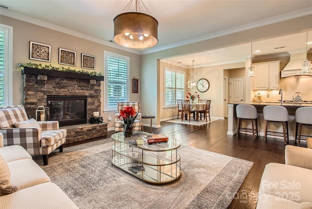 2599 Treeline Dr, Concord, NC 28027 - living area featuring a chandelier, dark wood finished floors, crown molding, and a stone fireplace