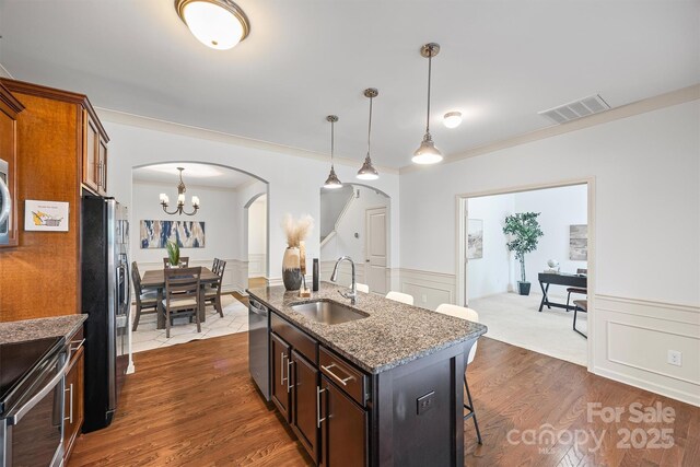 9706 Thyme Ct, Charlotte, NC 28214 - kitchen with arched walkways, a breakfast bar area, appliances with stainless steel finishes, stone countertops, and a chandelier