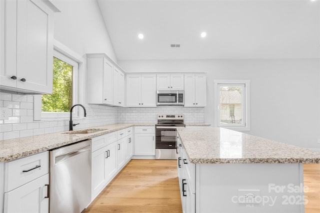 7 S Coulter Ave, Newton, NC 28658 - kitchen featuring appliances with stainless steel finishes, a kitchen island, light wood-style flooring, decorative backsplash, and recessed lighting