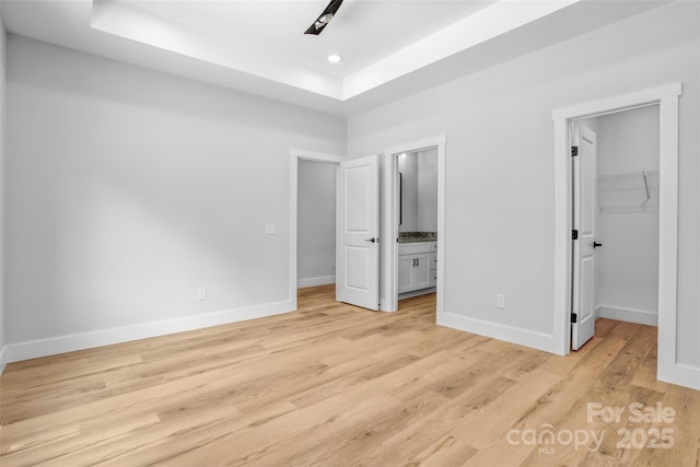 7 S Coulter Ave, Newton, NC 28658 - unfurnished bedroom with light wood finished floors, a raised ceiling, a spacious closet, ensuite bathroom, and a closet