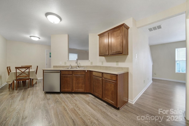 374 Morning Dew Dr, Concord, NC 28025 - kitchen featuring stainless steel dishwasher, light wood finished floors, light countertops, and brown cabinets