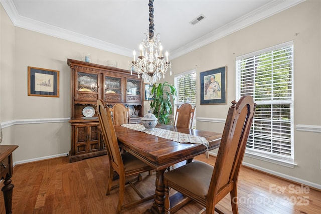 7029 Scuppernong Ct, Charlotte, NC 28215 - dining area with light wood-style flooring, crown molding, and a chandelier
