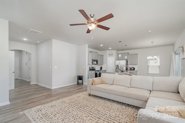 2014 Karen Woods Ln, Charlotte, NC 28216 - living area featuring light wood-style floors, a ceiling fan, a chandelier, recessed lighting, and arched walkways