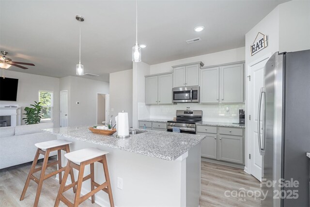 2014 Karen Woods Ln, Charlotte, NC 28216 - kitchen featuring stainless steel appliances, open floor plan, gray cabinetry, and light wood-style flooring