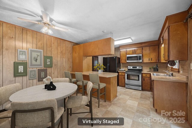 18 Progress Ln, Candler, NC 28715 - kitchen with appliances with stainless steel finishes, brown cabinets, light countertops, wood walls, and a ceiling fan
