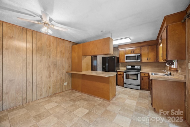 18 Progress Ln, Candler, NC 28715 - kitchen with appliances with stainless steel finishes, brown cabinetry, a peninsula, light countertops, and wooden walls