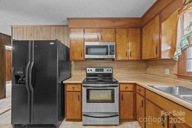 18 Progress Ln, Candler, NC 28715 - kitchen featuring stainless steel appliances, light countertops, brown cabinets, decorative backsplash, and a textured ceiling