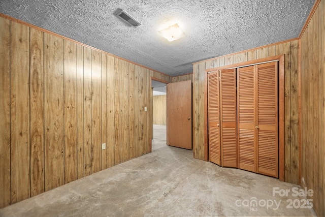 18 Progress Ln, Candler, NC 28715 - unfurnished bedroom featuring wooden walls, a closet, a textured ceiling, and carpet flooring