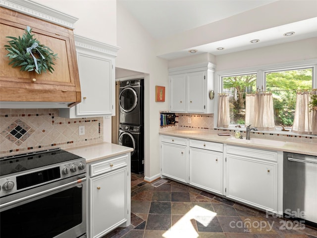 64 Wells Ln, Tryon, NC 28782 - kitchen featuring appliances with stainless steel finishes, stacked washing machine and dryer, light countertops, stone tile flooring, and vaulted ceiling