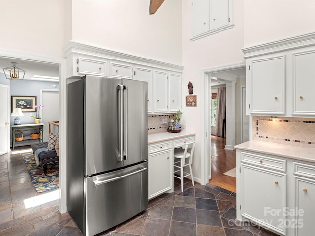 64 Wells Ln, Tryon, NC 28782 - kitchen with freestanding refrigerator, a towering ceiling, stone tile floors, light countertops, and white cabinets