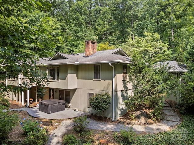 64 Wells Ln, Tryon, NC 28782 - back of house featuring a chimney, roof with shingles, a wooded view, a hot tub, and a wooden deck