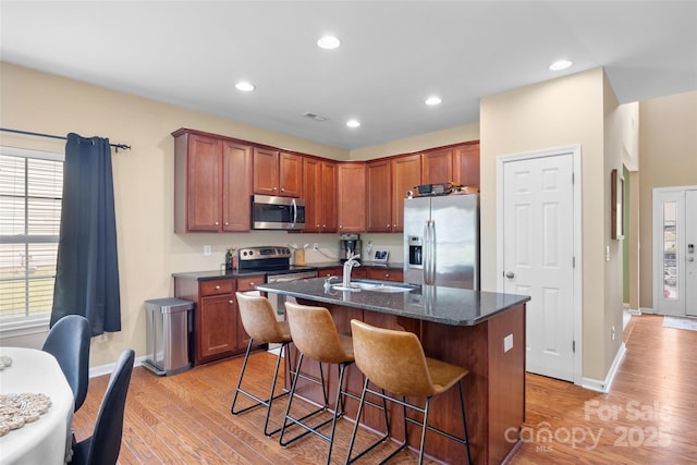 673 Stonehenge Dr, Rock Hill, SC 29730 - kitchen with appliances with stainless steel finishes, light wood-type flooring, a kitchen bar, an island with sink, and dark stone counters
