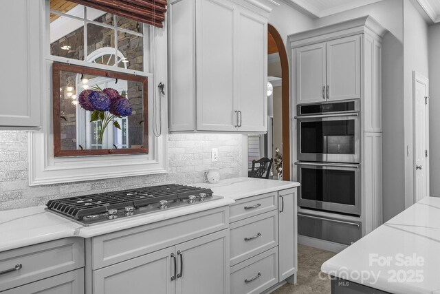 123 Yellow Jacket Cir, Mooresville, NC 28117 - kitchen featuring a warming drawer, appliances with stainless steel finishes, tasteful backsplash, arched walkways, and crown molding