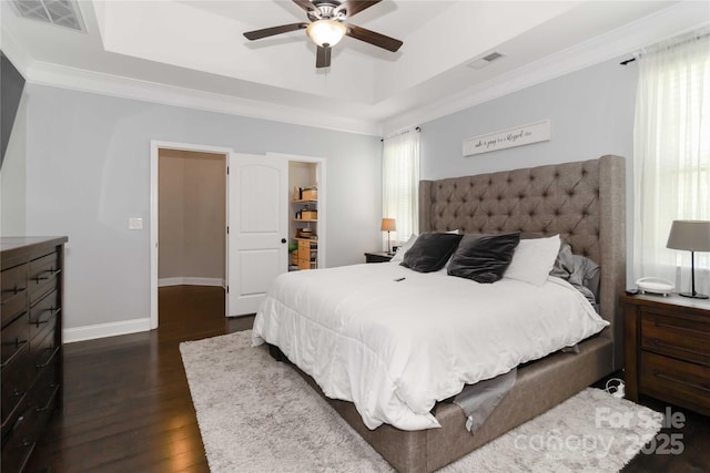 1041 Verbena Ct, Tega Cay, SC 29708 - bedroom featuring dark wood-type flooring, multiple windows, ornamental molding, a raised ceiling, and a walk in closet