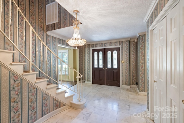 630 Burrage Rd NE, Concord, NC 28025 - foyer with wallpapered walls, stairs, a textured ceiling, crown molding, and a chandelier