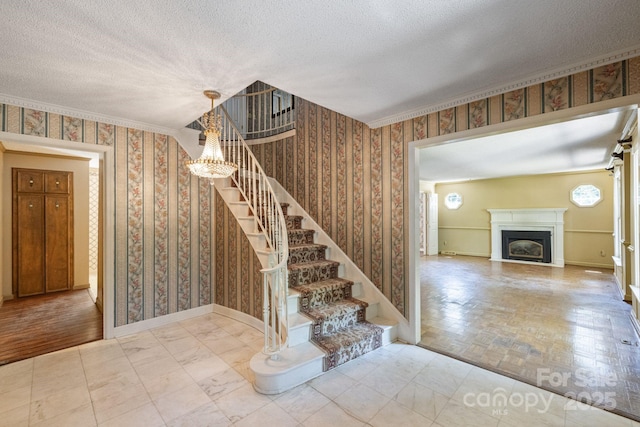 630 Burrage Rd NE, Concord, NC 28025 - stairway featuring wallpapered walls, a textured ceiling, a fireplace, and a chandelier