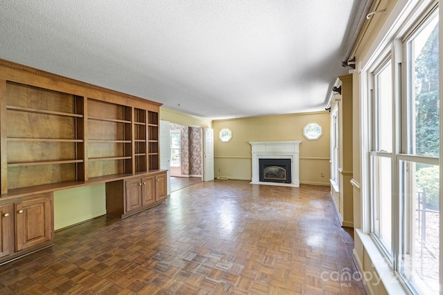 630 Burrage Rd NE, Concord, NC 28025 - unfurnished living room with built in study area, a fireplace with flush hearth, and a textured ceiling