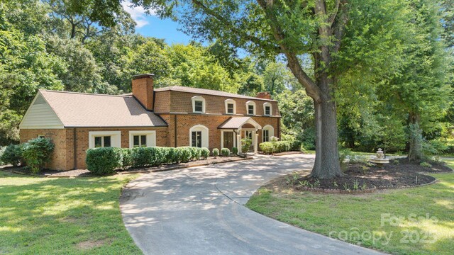 630 Burrage Rd NE, Concord, NC 28025 - view of front of house with a chimney, curved driveway, brick siding, and a front lawn