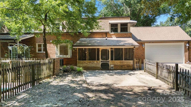 630 Burrage Rd NE, Concord, NC 28025 - view of front facade featuring a garage, a sunroom, a shingled roof, brick siding, and driveway