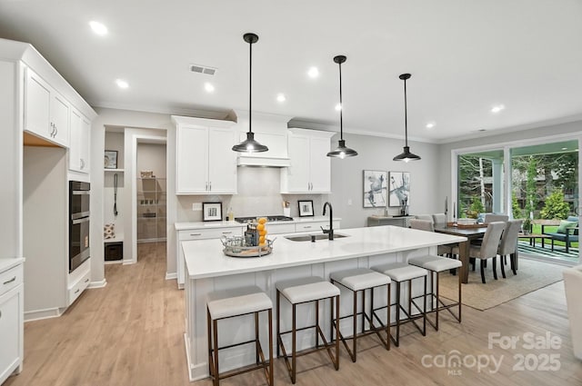 9945 Cask Way, Huntersville, NC 28078 - kitchen with light wood finished floors, appliances with stainless steel finishes, ornamental molding, a breakfast bar, and light countertops