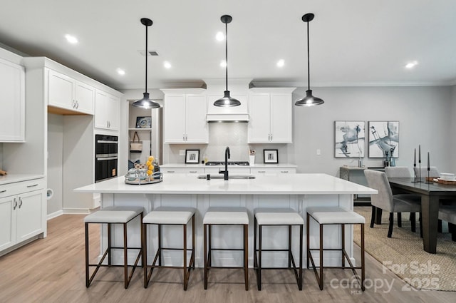 9945 Cask Way, Huntersville, NC 28078 - kitchen featuring light countertops, white cabinetry, ornamental molding, light wood finished floors, and a kitchen breakfast bar