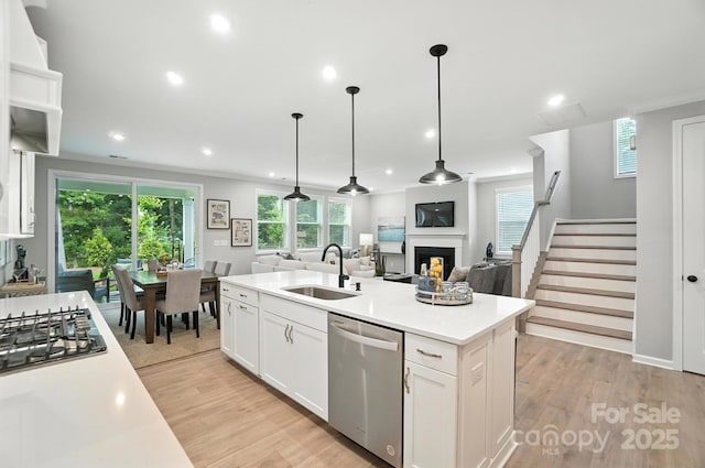 9945 Cask Way, Huntersville, NC 28078 - kitchen featuring appliances with stainless steel finishes, a fireplace, open floor plan, light wood finished floors, and an island with sink
