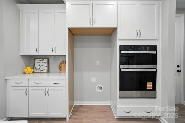 9945 Cask Way, Huntersville, NC 28078 - kitchen with stainless steel double oven, light wood finished floors, light countertops, white cabinets, and decorative backsplash