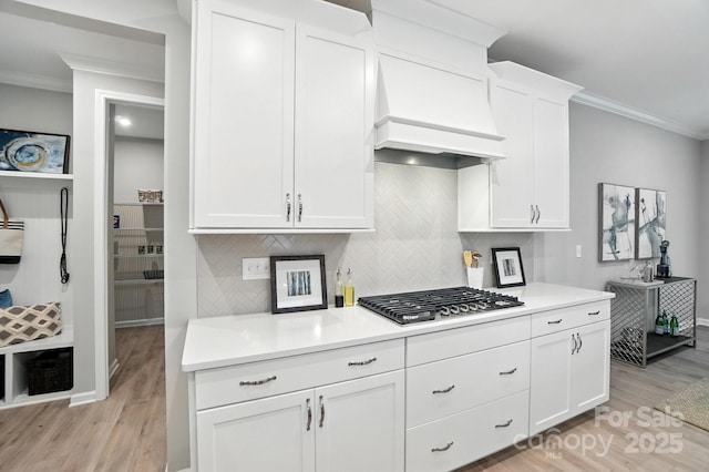 9945 Cask Way, Huntersville, NC 28078 - kitchen featuring stainless steel gas cooktop, crown molding, light wood-style flooring, custom range hood, and white cabinetry