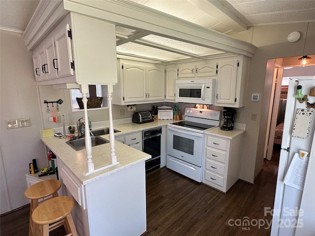104 Pine St Unit 201, New London, NC 28127 - kitchen with white appliances, a peninsula, dark wood finished floors, white cabinetry, and a kitchen bar