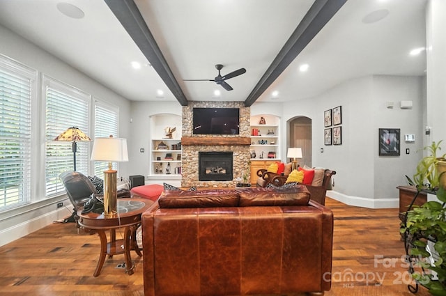 5005 Craftsman Ridge Dr, Matthews, NC 28104 - living room featuring a ceiling fan, beamed ceiling, arched walkways, a fireplace, and wood finished floors