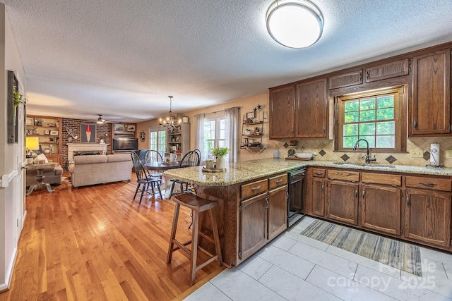 302 Redwood Pl, Lenoir, NC 28645 - kitchen featuring black dishwasher, a peninsula, a textured ceiling, a brick fireplace, and plenty of natural light